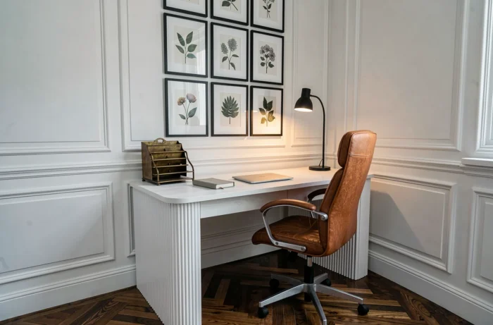 Bureau à domicile moderne dans un appartement haussmannien avec bureau en chêne cannelé, chaise en cuir cognac et mur de cadres botaniques